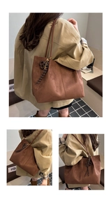 Detailed view of the brown suede tote bag featuring slim leather handles and decorative charm