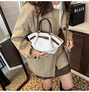 Detail of white and brown bicolor tote bag with side buckle on khaki outfit
