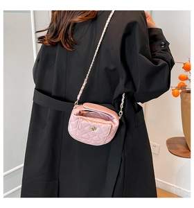 Close-up of pink quilted mini crossbody bag with gold flower clasp on a long coat