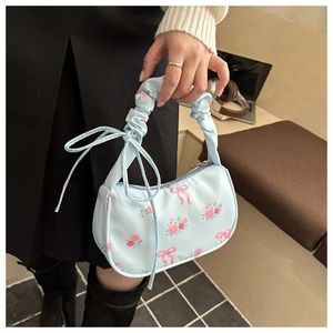 Close-up of light blue floral handbag with pink rose patterns and pleated handle detail
