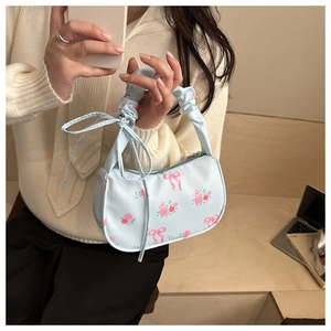 Detail of light blue floral handbag with pink rose prints and ruffled handle with bows