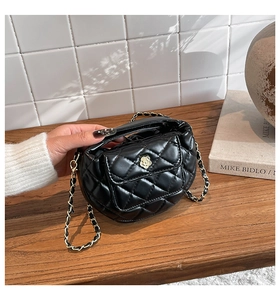 Close-up of black quilted leather bag with camellia flower metal lock and chain strap