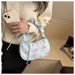 Detail of light blue floral handbag with scrunchie handle and pink rose pattern