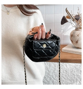 Detail of black quilted leather mini moon bag with gold floral buckle and chain strap