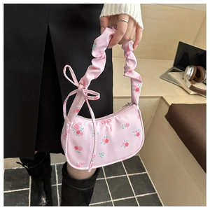 Detailed shot of pink floral underarm bag with pleated handle and bow tie detail