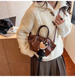 Detail of dark brown leather mini tote bag with Hello Kitty charm and belt buckle design
