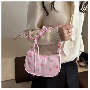 Detail of floral underarm bag featuring pink rose patterns and ruched handle design