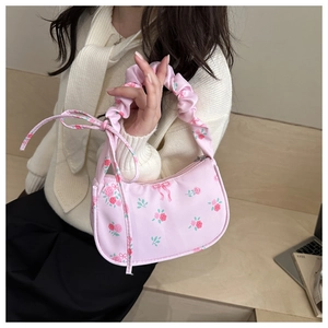 Detail of pink floral handbag featuring a scrunchie strap and delicate bow decoration