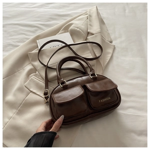 Detail of a dark brown bowling bag with double front flap pockets and gold-tone metal hardware