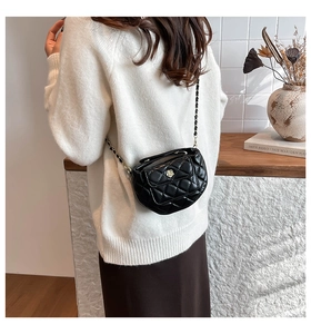 Quilted black leather half-moon crossbody bag with golden camellia buckle on a model