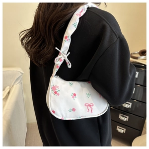 Detail of floral canvas hobo bag featuring pink roses, green leaves and bow patterns