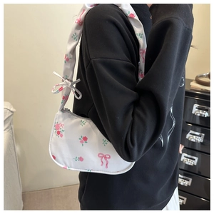 Detail of white baguette bag with pink rose prints and a decorative bow on the shoulder strap