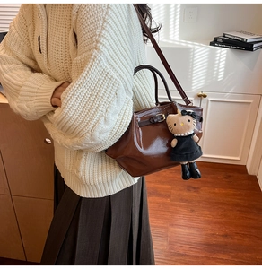 Detail of dark brown glossy mini tote bag with adjustable strap and cute plush charm