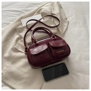 Detail view of burgundy vintage bowling bag with front pockets and fashion text