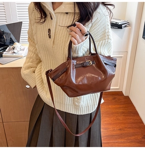 Detail of vintage brown glossy leather bucket bag with gold buckle and smooth texture