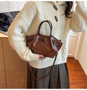 Detailed view of brown glossy shoulder bag with pleated texture and stylish metal buckle