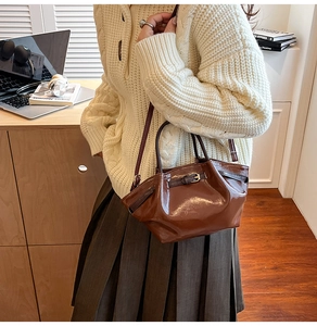 Chic dark brown glossy pleated handbag with shoulder strap in a stylish office setting