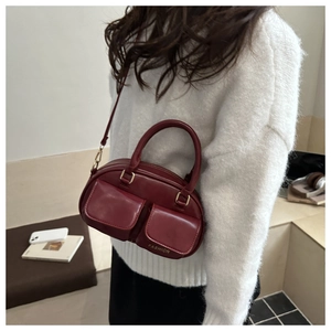 Detail of burgundy leather bowling bag with gold hardware and two front pockets