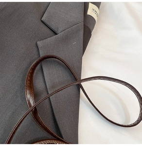 Close-up of deep gray crossbody bag texture with fine stitching and brown leather strap