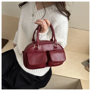 Detail of burgundy pillow bag showing dual front pockets and gold metallic ring hardware