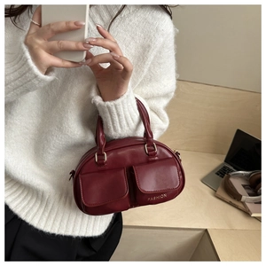 Detail of dark red bowling bag with golden hardware and fashion pocket on beige sweater