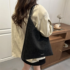 Sac fourre-tout minimaliste en daim noir avec logo FASHION présenté porté à l'épaule
