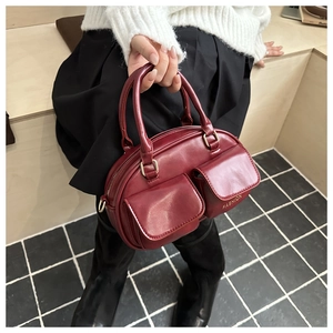 Close-up of burgundy leather boston bag with dual front pockets and fashion branding