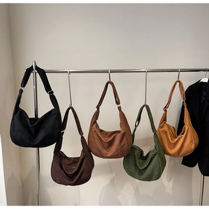 Row of five colorful minimalist crescent hobo bags hanging on a simple metal rack