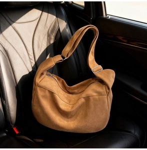 Close-up of brown suede tote bag with metal buckle on car seat under natural light