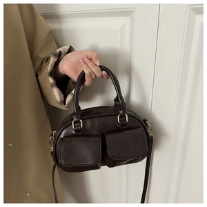 Detail of coffee brown bowling bag featuring dual front pockets and fashion text
