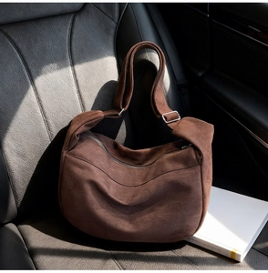 Close-up of brown suede hobo bag texture and silver metal buckle on a car seat