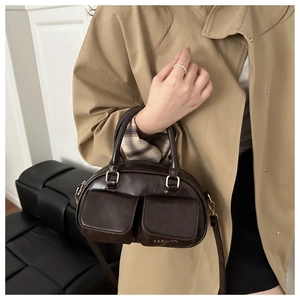 Detail of dark brown retro bowling bag with fashion embossed pockets and gold buckles