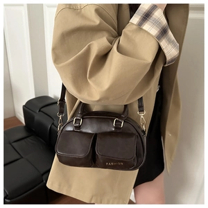 Detail of vintage brown bowling bag worn with a trench coat showing the front pockets