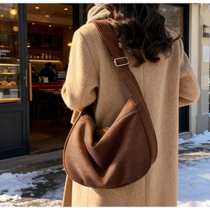 Detail of a brown suede hobo bag with adjustable wide strap shown in winter street setting