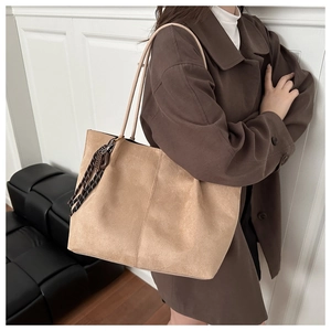 Detail of light brown matte suede tote bag featuring slim straps and woven accent charm
