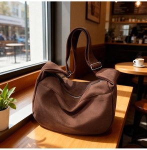 Close-up of brown suede hobo bag with adjustable strap in a cozy cafe setting