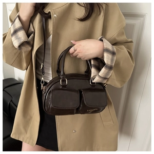 Detailed view of dark brown glossy leather handbag featuring dual front pockets and gold hardware