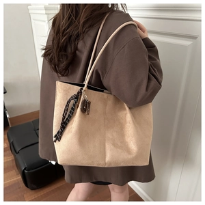 Detailed side view of khaki suede tote bag with woven tassel charm and slim shoulder straps