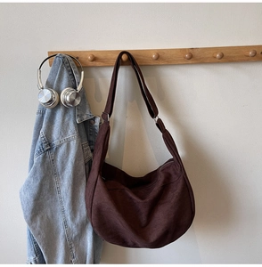 Close-up of brown canvas crescent tote bag featuring adjustable strap and metal zipper