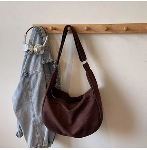 Detail of dark brown suede tote bag with adjustable silver buckle on wood hook