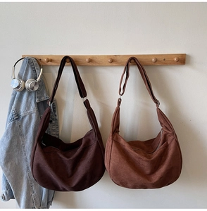 Close-up of suede shoulder bags in dark brown and caramel hanging on wooden hooks