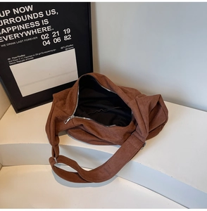 Detailed view of large dark brown suede tote bag with silver zipper on white stand