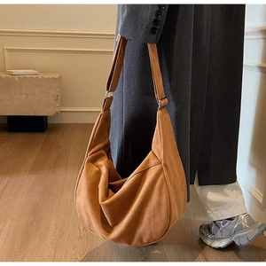 Caramel suede large crescent tote bag worn over a grey coat for casual urban style