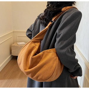 Detail of a large suede hobo bag in brown, showing the spacious slouchy crescent structure