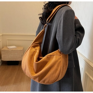 Large caramel suede tote bag shown on model wearing grey coat for autumn winter fashion