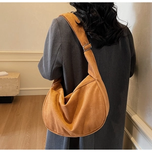 Detail of orange suede hobo bag showing the wide strap and silver metal buckle