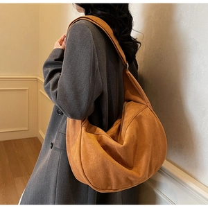 Detailed view of caramel suede hobo bag on shoulder showing large capacity and soft texture