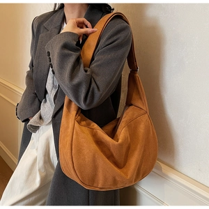 Detail of caramel suede hobo bag worn by model over a grey wool blazer and white pants