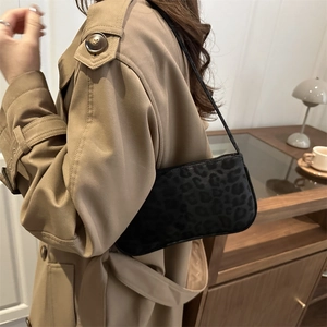 Petit sac à bandoulière chic à motif léopard noir porté par un mannequin en intérieur