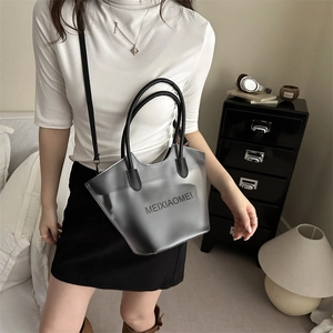 Sac cabas élégant en PVC gris semi-transparent avec poignées noires porté par un mannequin